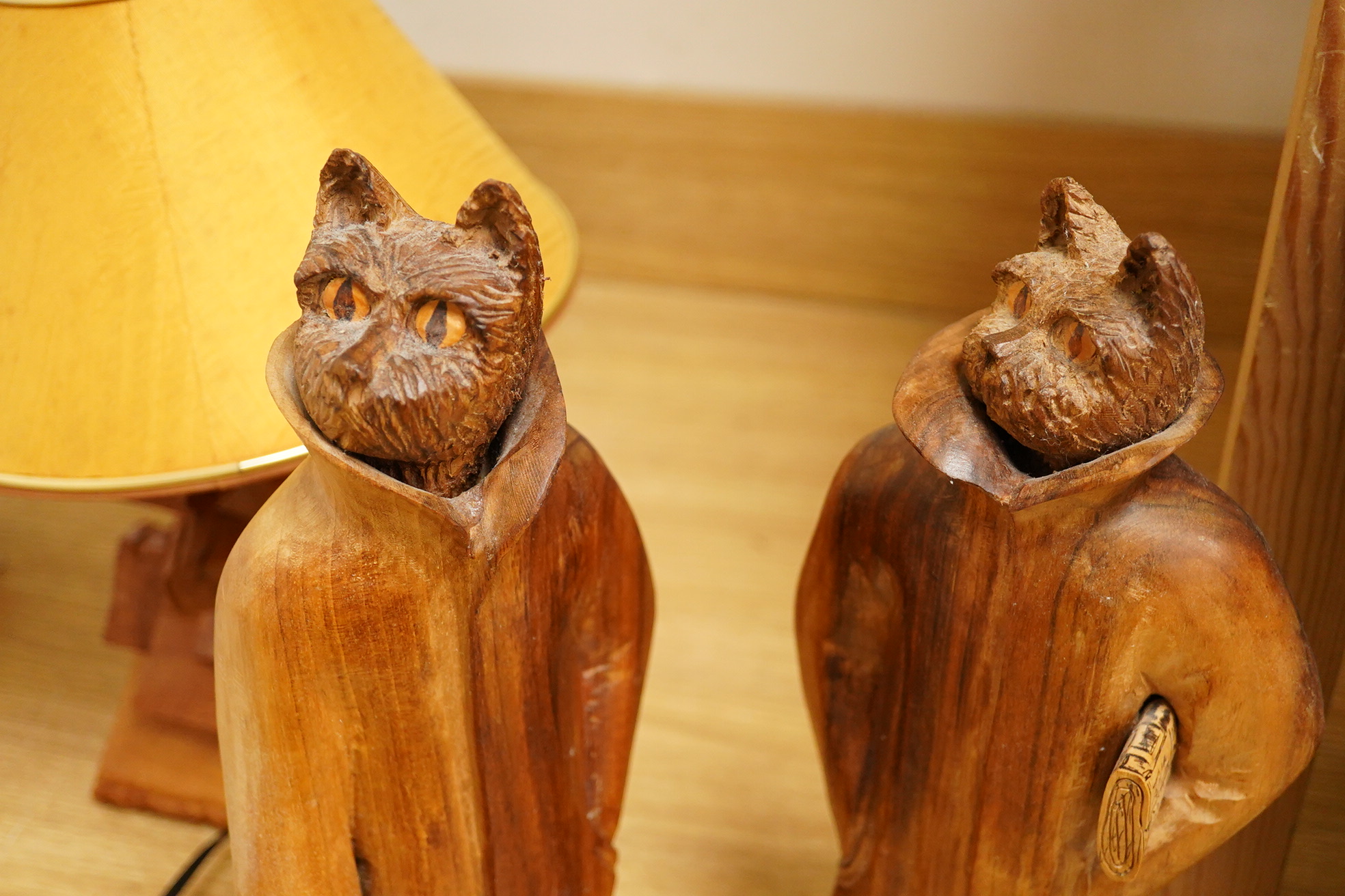 Pierre Decorse (b.1953), a pair of carved hardwood cats and a novelty lamp modelled as a stack of books, with shade, largest overall 36cm high